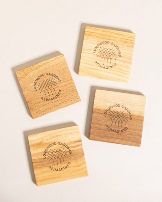 Four wood coasters with the text Longwood Gardens Reimagined stamped into them.